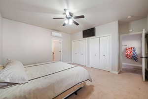 Bedroom with two closets, a ceiling fan, and light carpet