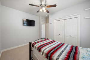 Carpeted bedroom with a ceiling fan and a closet