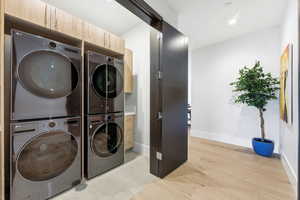 Laundry area featuring light wood-type flooring, recessed lighting, and stacked washer / dryer
