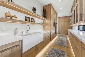 Kitchen featuring light wood-style floors, light stone counters, modern cabinets, glass insert cabinets, and open shelves