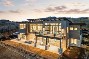 Back of property at dusk with a patio, a fire pit, a mountain view, and stone siding