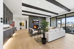 Living area featuring beam ceiling, light wood-style floors, a large fireplace, and recessed lighting