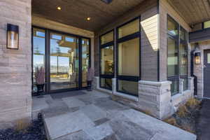 Entrance to property featuring stone siding and a patio