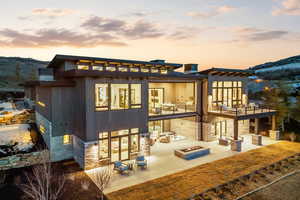 Back of house at dusk with an outdoor fire pit, a patio area, and a mountain view
