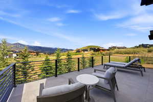 Expansive outdoor terrace featuring large format tile flooring, a horizontal slat railing system, and surrounding natural landscaping