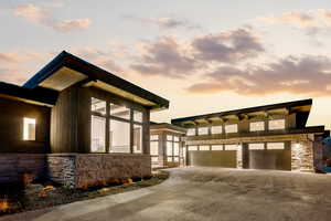 View of property exterior featuring stone siding, a garage, driveway, and a sunroom