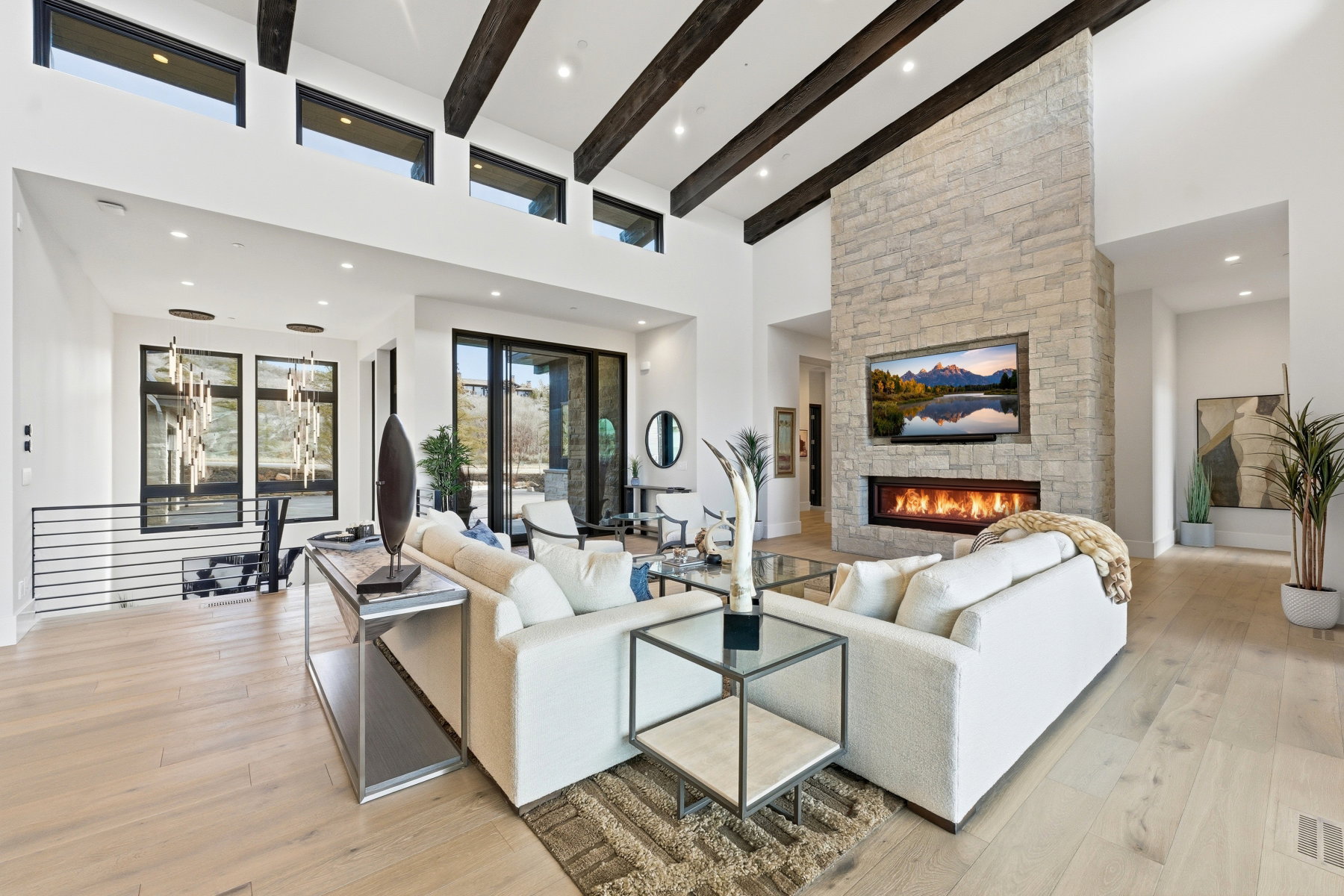 Living room with a stone fireplace, light wood-type flooring, vaulted ceiling, and recessed lighting