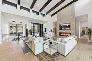 Living room with a stone fireplace, light wood-type flooring, vaulted ceiling, and recessed lighting