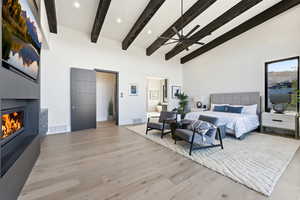 Bedroom featuring a large fireplace, light wood-style floors, ceiling fan, and ensuite bath