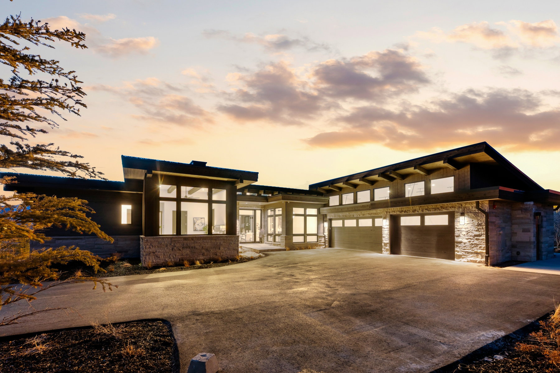 View of front facade featuring stone siding, concrete driveway, and a garage