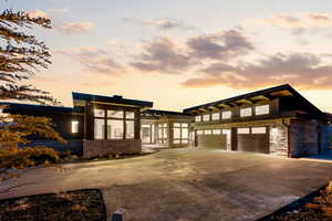 View of front facade featuring stone siding, concrete driveway, and a garage