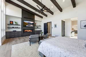 Bedroom with light wood-type flooring, a fireplace, a ceiling fan, and vaulted ceiling