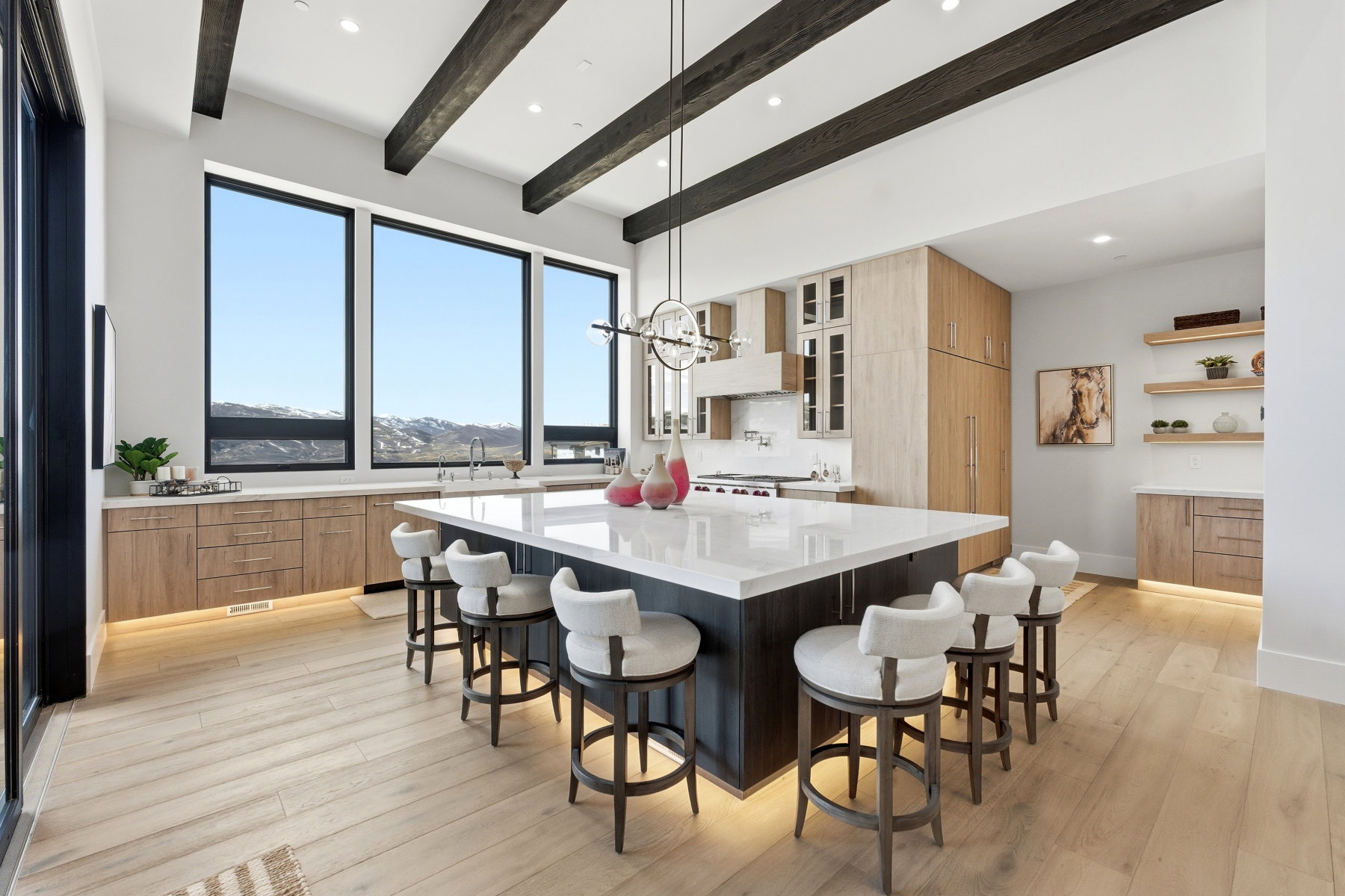 Kitchen with a breakfast bar, light wood finished floors, a spacious island, light stone countertops, and two tone color scheme
