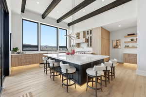 Kitchen with a breakfast bar, light wood finished floors, a spacious island, light stone countertops, and two tone color scheme