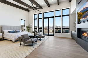 Bedroom with a glass covered fireplace, light wood-style flooring, and access to outside