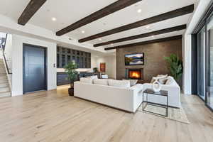 Living room featuring a fireplace, light wood-style flooring, recessed lighting, and beamed ceiling