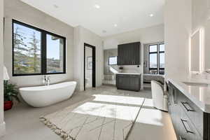 Bathroom featuring a soaking tub, vanity, plenty of natural light, and recessed lighting