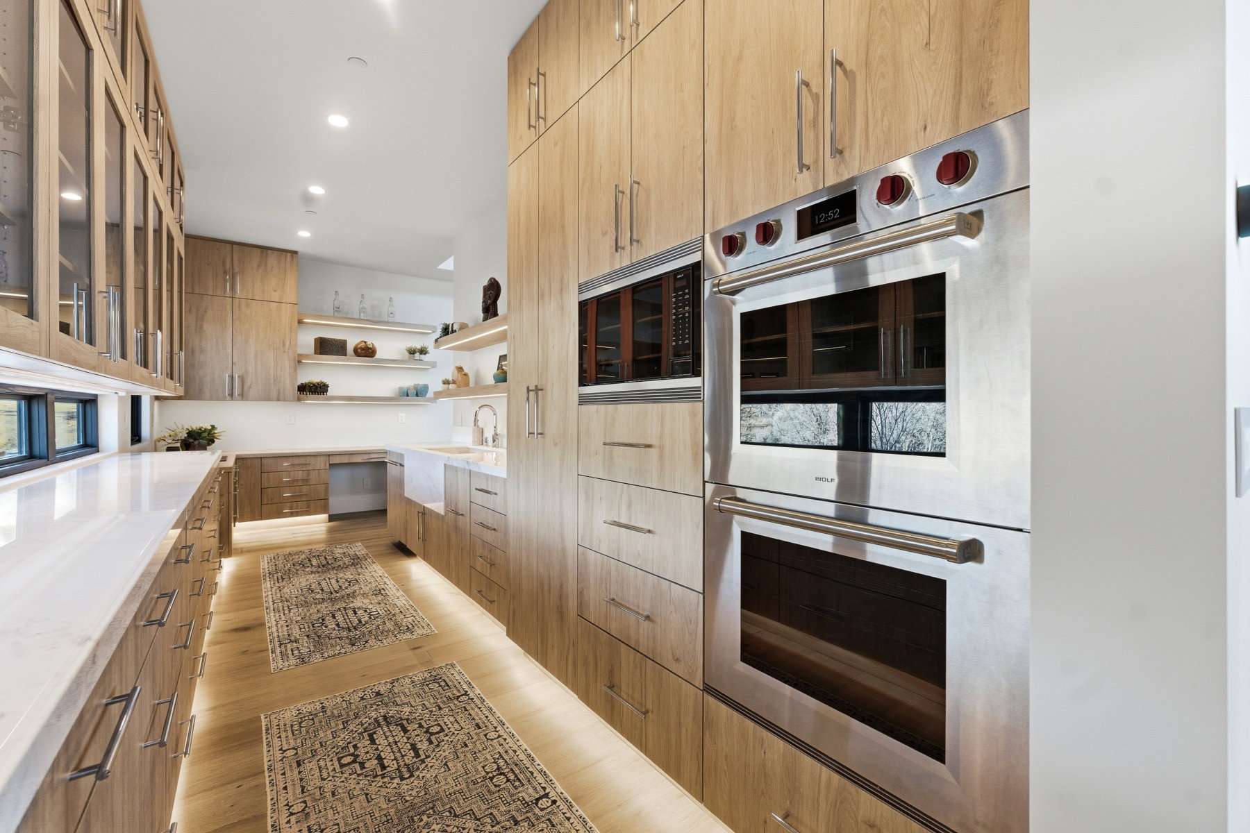 Kitchen featuring stainless steel appliances, open shelves, modern cabinets, glass fronted cabinets, and light wood-style flooring
