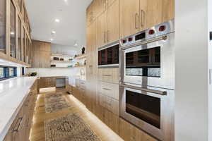 Kitchen featuring stainless steel appliances, open shelves, modern cabinets, glass fronted cabinets, and light wood-style flooring