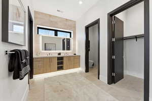 Full bath with double vanity, a spacious closet, and light tile patterned floors