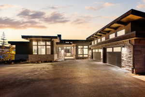 View of front facade with stone siding and driveway