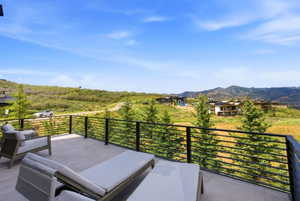 Outdoor terrace with neutral-toned tile flooring, black horizontal bar railings, and a mountainous backdrop