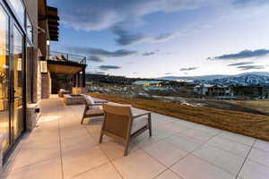 Patio terrace at dusk with a fire pit, a mountain view, and a patio area