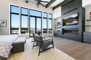 Bedroom with light wood-style floors, a glass covered fireplace, and access to exterior