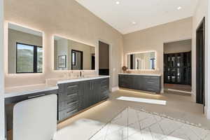 Bathroom featuring two vanities, concrete floors, recessed lighting, and a high ceiling