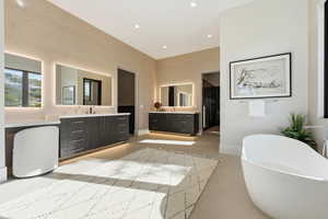 Full bathroom featuring two vanities, a soaking tub, a high ceiling, recessed lighting, and finished concrete floors