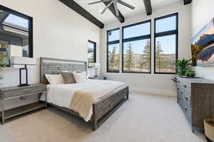 Bedroom featuring light carpet, beamed ceiling, and a ceiling fan
