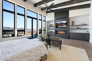 Bedroom with a fireplace, light wood finished floors, access to exterior, and a ceiling fan