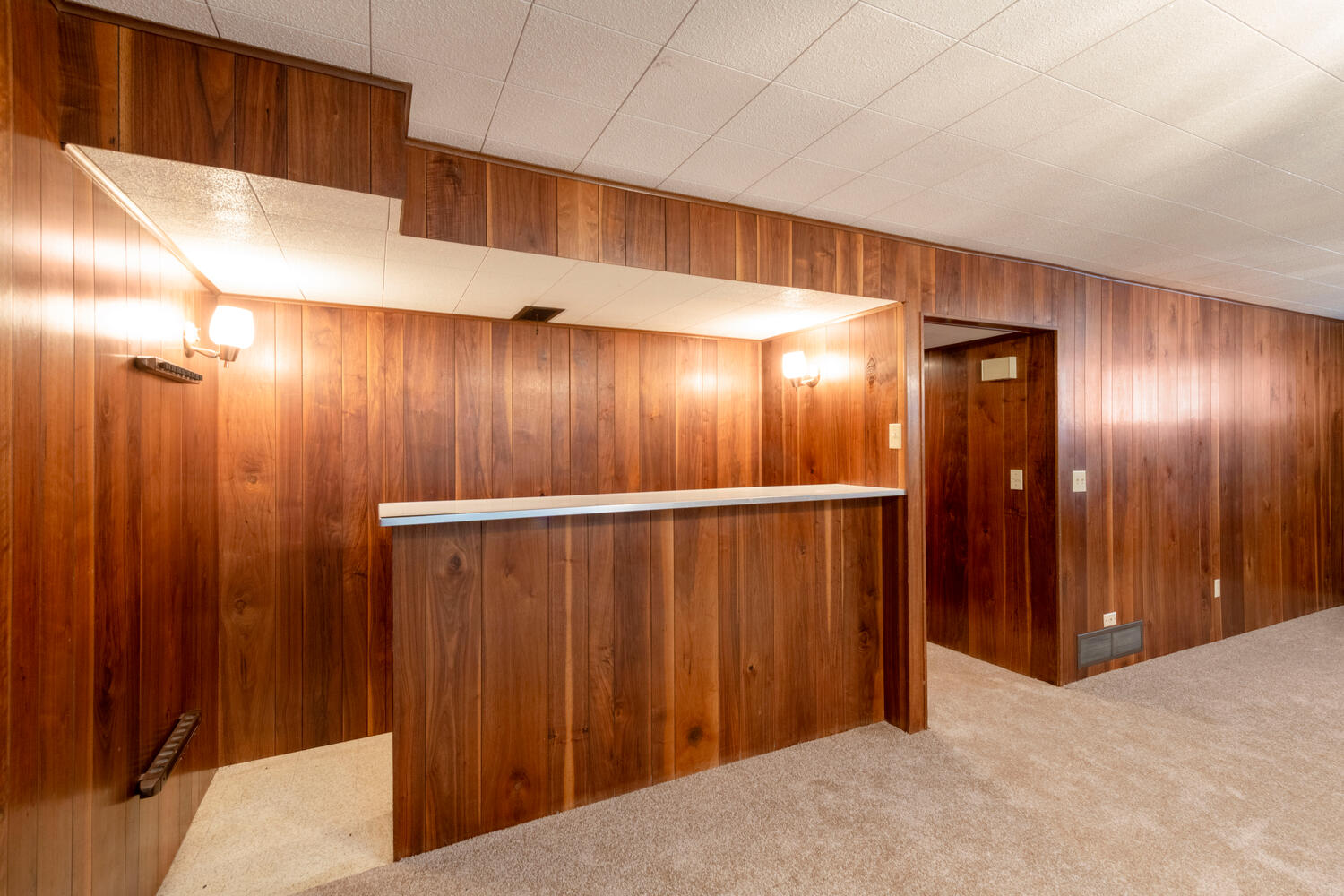 Bar area with carpet flooring and wooden walls