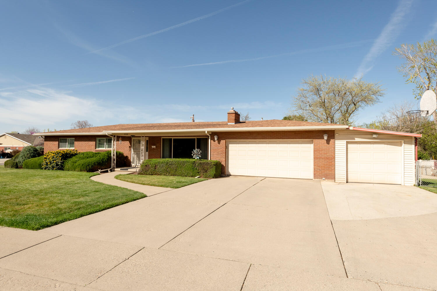 Ranch-style home with brick siding, an attached garage, concrete driveway, a front yard, and a chimney