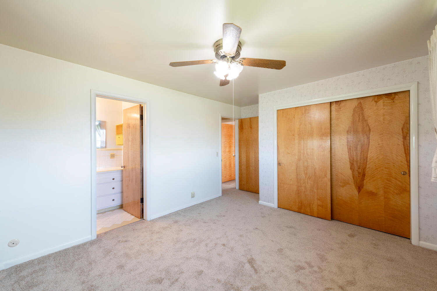 Unfurnished bedroom with light colored carpet, a ceiling fan, connected bathroom, and a closet