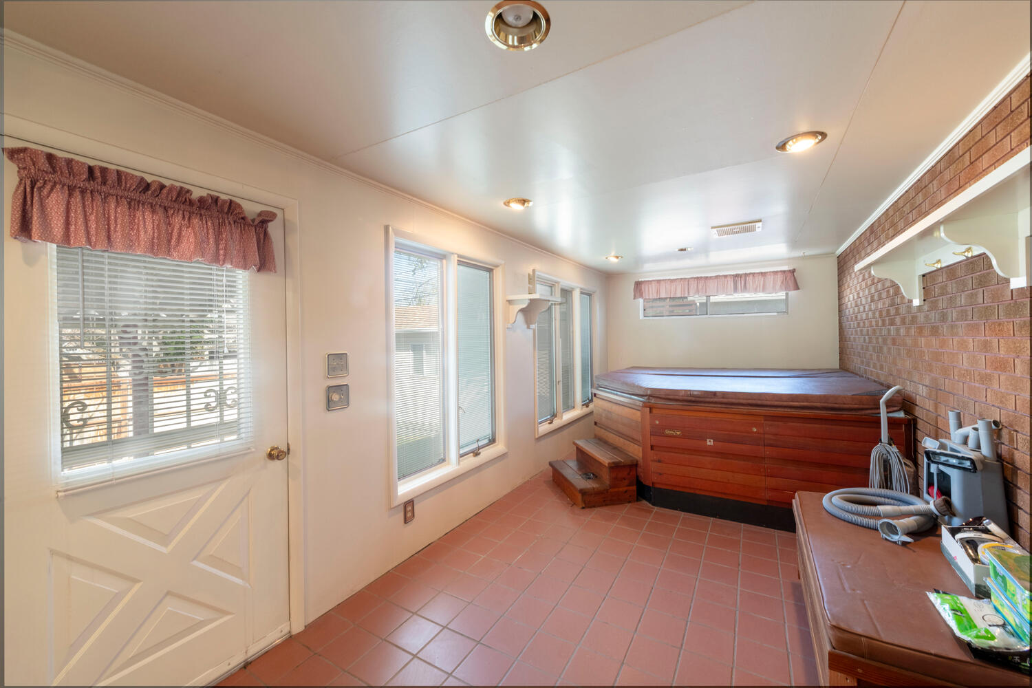 Doorway to outside featuring brick wall, tile patterned flooring, and healthy amount of natural light