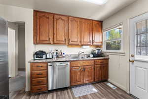 Kitchen featuring wood finish cabinetry, stainless steel appliances, dark wood-style floors, and light countertops