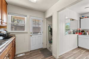 Kitchen featuring light wood-type flooring, wood finish cabinetry, light stone countertops, and white cabinetry