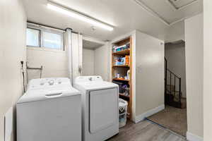 Laundry room featuring washer and dryer, light wood-type flooring, and a textured ceiling