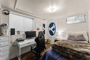 Bedroom featuring a textured ceiling, carpet flooring, and an office area