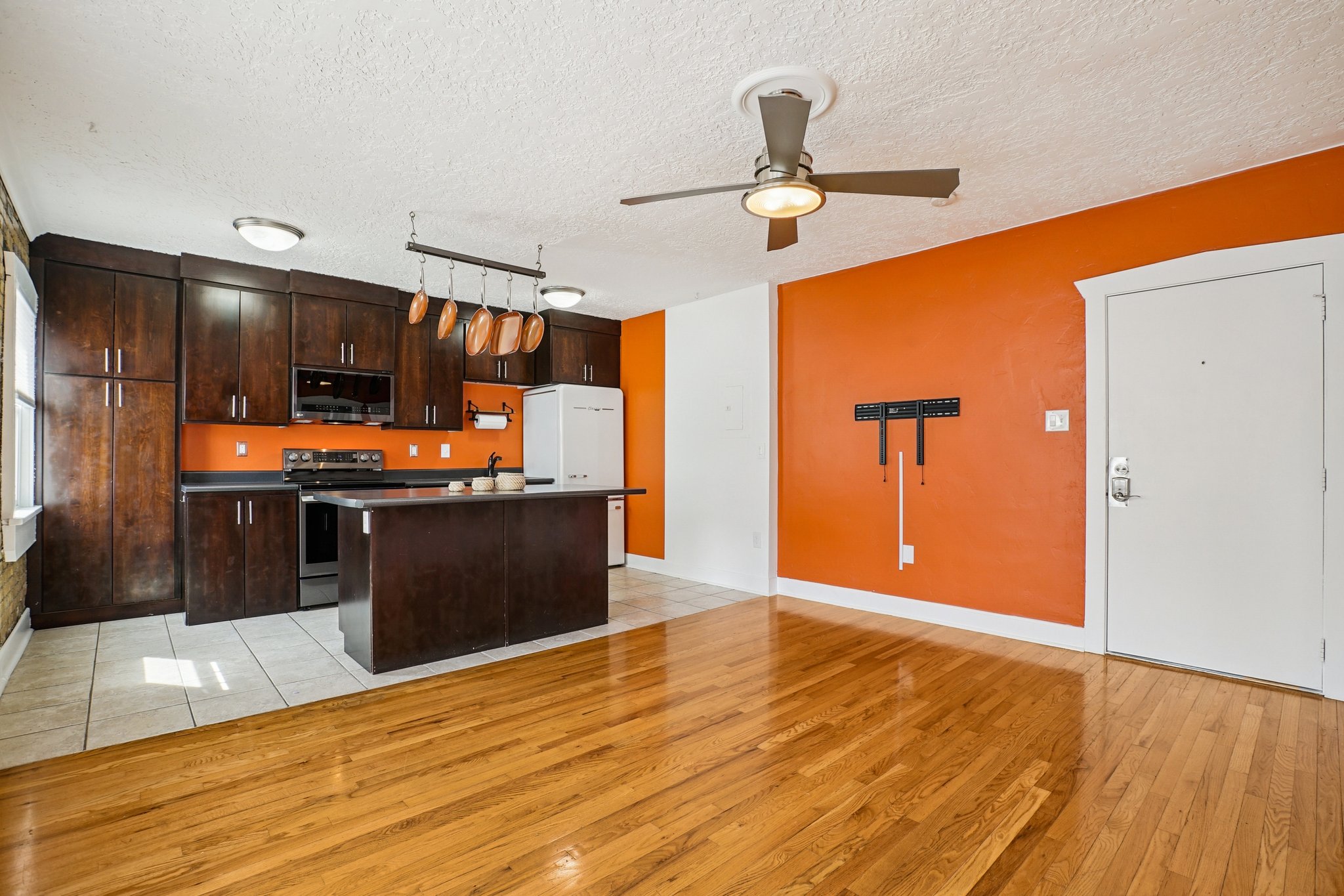 Kitchen with dark wood finish cabinetry, a kitchen island, dark countertops, stainless steel appliances, and track lighting