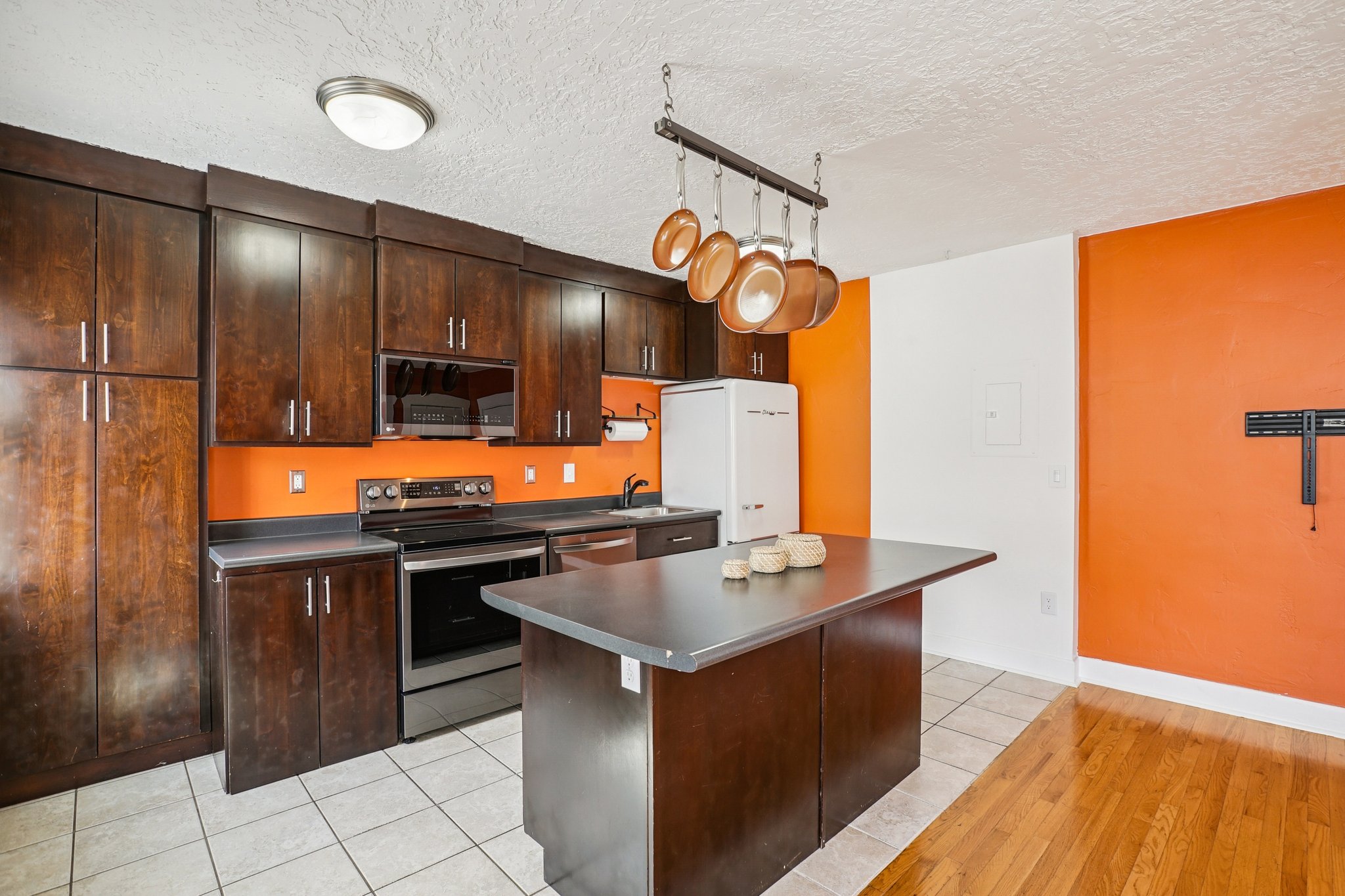 Kitchen featuring dark wood finish cabinets, stainless steel appliances, light tile patterned flooring, track lighting, and a kitchen island