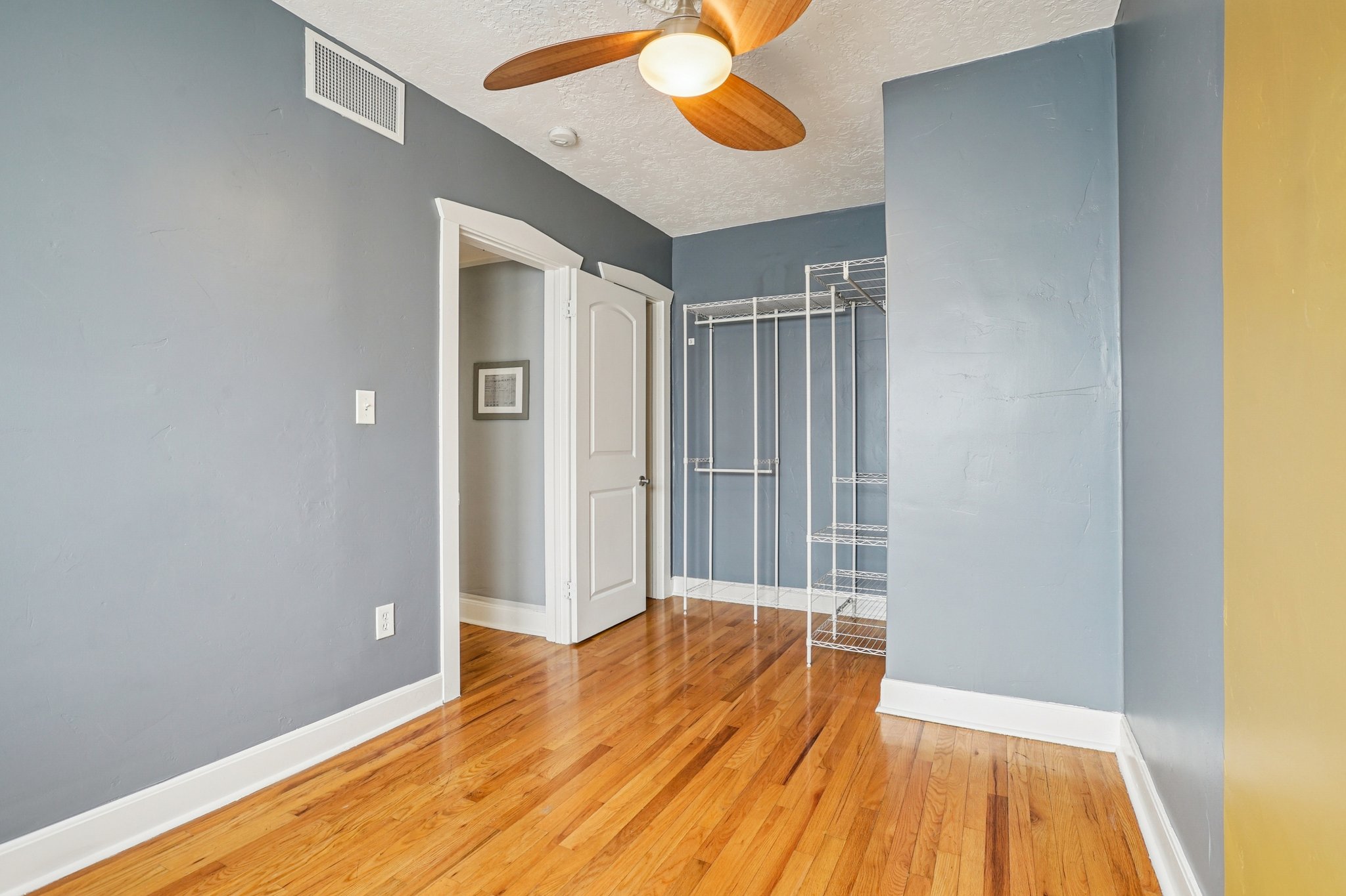 Empty room featuring light wood finished floors, a ceiling fan, and a textured ceiling