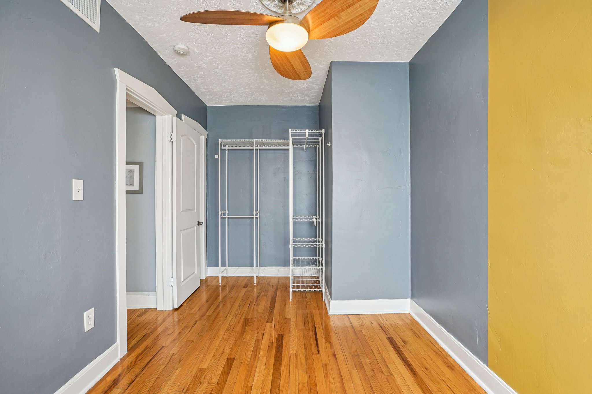 Unfurnished bedroom featuring a closet, light wood-type flooring, a textured ceiling, and a ceiling fan