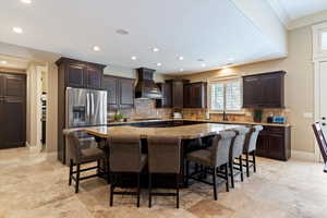 Kitchen with backsplash, dark stone countertops, dark wood finish cabinetry, a center island, and open floor plan