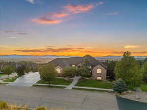 View of front facade featuring brick siding, a yard, a mountain view, an attached garage, and concrete driveway