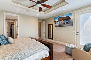 Carpeted bedroom with a tray ceiling, recessed lighting, and a ceiling fan