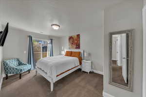 Carpeted bedroom featuring a textured ceiling and access to outside