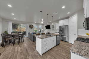 Kitchen with open floor plan, white cabinetry, dark stone counters, and stainless steel appliances