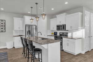 Kitchen with stainless steel appliances, a kitchen breakfast bar, and white cabinets